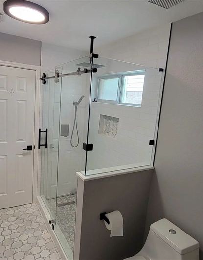 L-shaped frameless shower door with black rollers installed in a Hialeah, FL home
